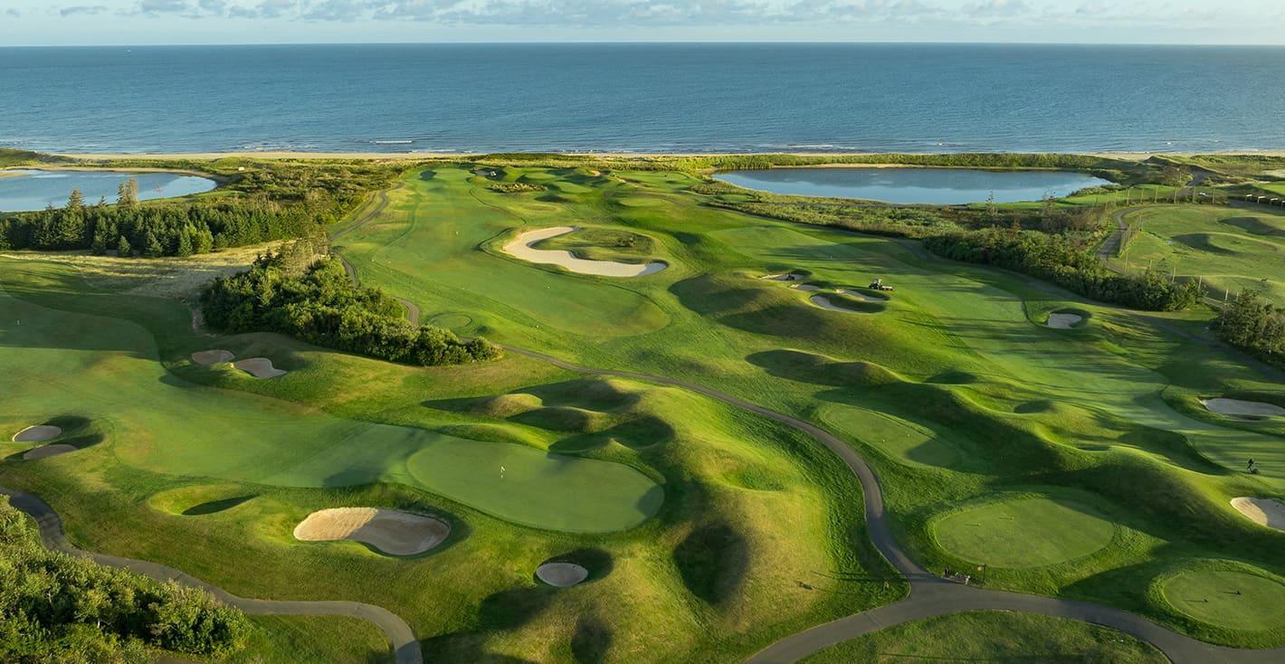 Aerial view of The Links at Crowbush Cove, with fairways, bunkers, and the Gulf of St. Lawrence beyond the dunes